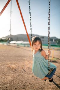 Cute girl sitting on swing at playground