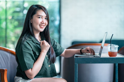 Portrait of young woman using mobile phone while sitting at home