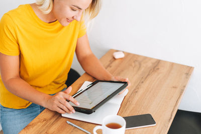 Young woman studies cryptocurrency charts and stock quotes on digital tablet at home