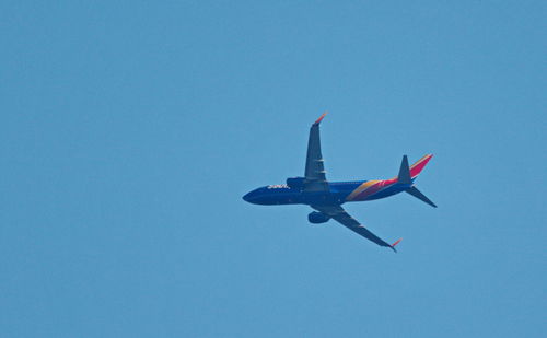 Low angle view of airplane against clear blue sky