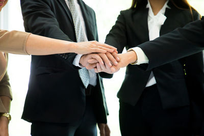 Midsection of business colleagues stacking hands