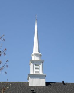 Low angle view of church steeple against clear blue sky