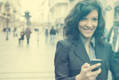 Portrait of a smiling young woman using smart phone