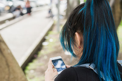 View of the back of a beautiful young blue-haired university student looking at her social networks