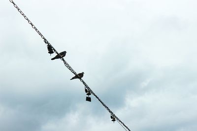 Low angle view of crane against cloudy sky