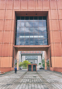 Man walking on footpath by building