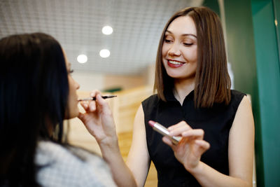 A make-up artist makes makeup for a girl in the salon, applies lipstick, completes the image. 