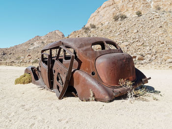 Old rusty metal on sand in desert against sky