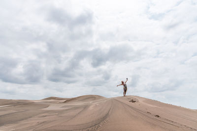 Photo with copy space of a woman gesturing freedom in the middle of a desert in a cloudy day