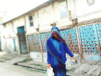 Rear view of woman walking against building