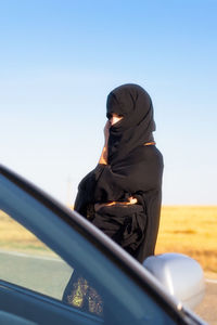 Woman wearing hijab standing against sky