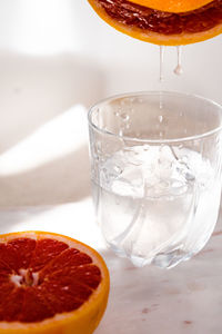 Close-up of grapefruit squeezing in glass over white background