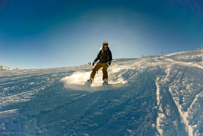 Man skiing on snow covered mountain against sky