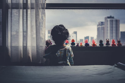 Rear view of girl playing with toys on window sill at home