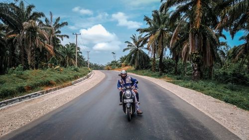 People riding motorcycle on road against sky