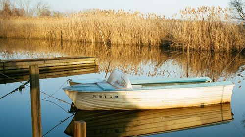Close-up of boat moored in lake against sky