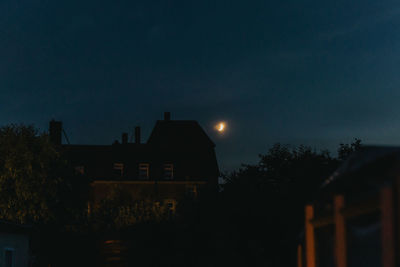 Silhouette trees and buildings against sky at night