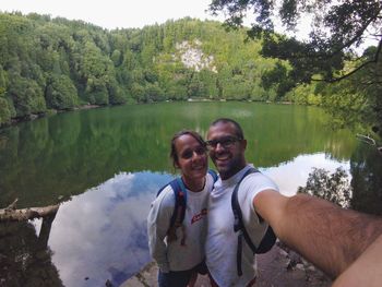 Portrait of happy couple against calm lake