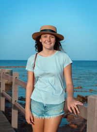 Portrait of young woman standing by sea against clear sky