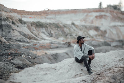 Full length of man sitting on rock