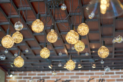 Low angle view of illuminated light bulbs hanging from ceiling
