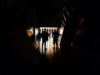 Silhouette people walking in illuminated building