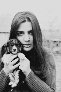 Portrait of young woman holding puppy