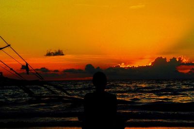 Rear view of silhouette man against orange sky