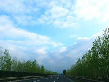 Road by trees against sky