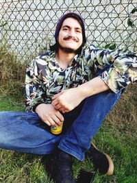 Portrait of smiling young man sitting on field