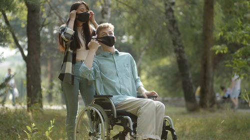 Young woman wearing mask with handicapped boyfriend at park