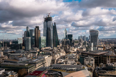 Aerial view of buildings in city against cloudy sky