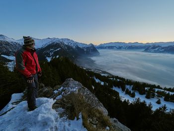 Man standing on snow covered mountain against sky