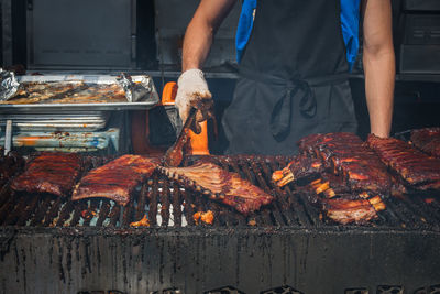 Midsection of man preparing food on barbecue grill