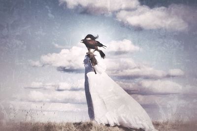 Low angle view of girl jumping against cloudy sky