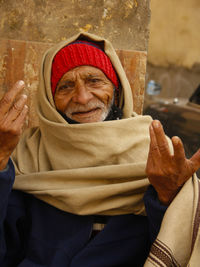 Portrait of man gesturing while sitting against wall