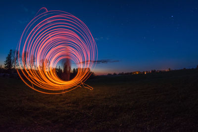 Light trails on field against sky at night