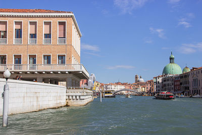 View of buildings by canal against sky