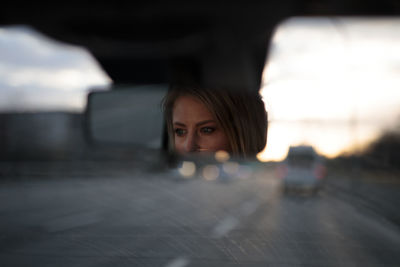 Portrait of young woman standing in car