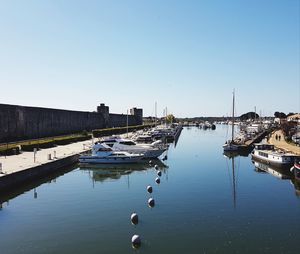 Boats moored at harbor against clear sky