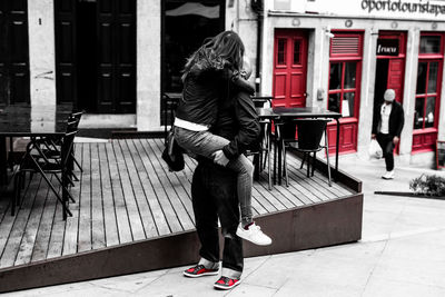 Full length rear view of woman walking on footpath in city