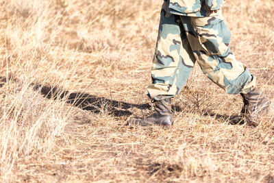 Low section of soldier walking on field