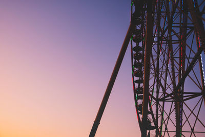 Low angle view of rollercoaster against sky at sunset