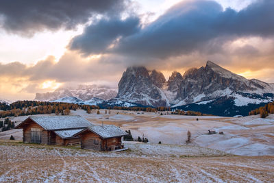 Houses on snowcapped mountain against sky during sunset