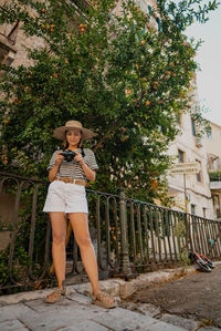 Portrait of smiling woman standing against tree