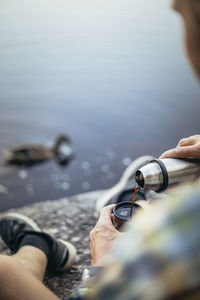 Mature man pouring coffee while sitting at lake