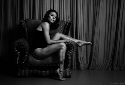 Portrait of seductive woman sitting on chair at home
