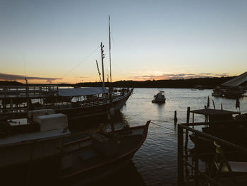 Boats moored in harbor at sunset