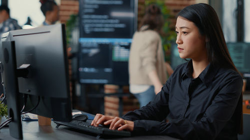 Young woman using desktop pc at office