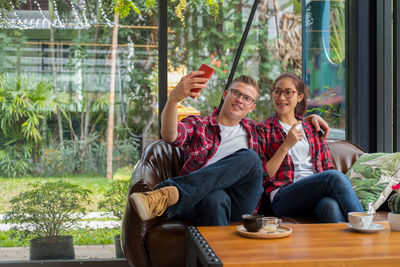 Man taking selfie with girlfriend while sitting in restaurant